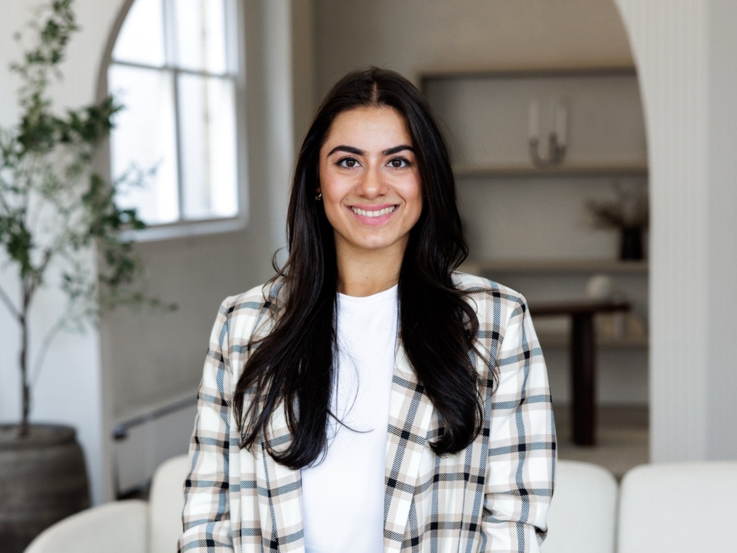Felicia Scaringi wearing a plaid jacket standing in a modern room.