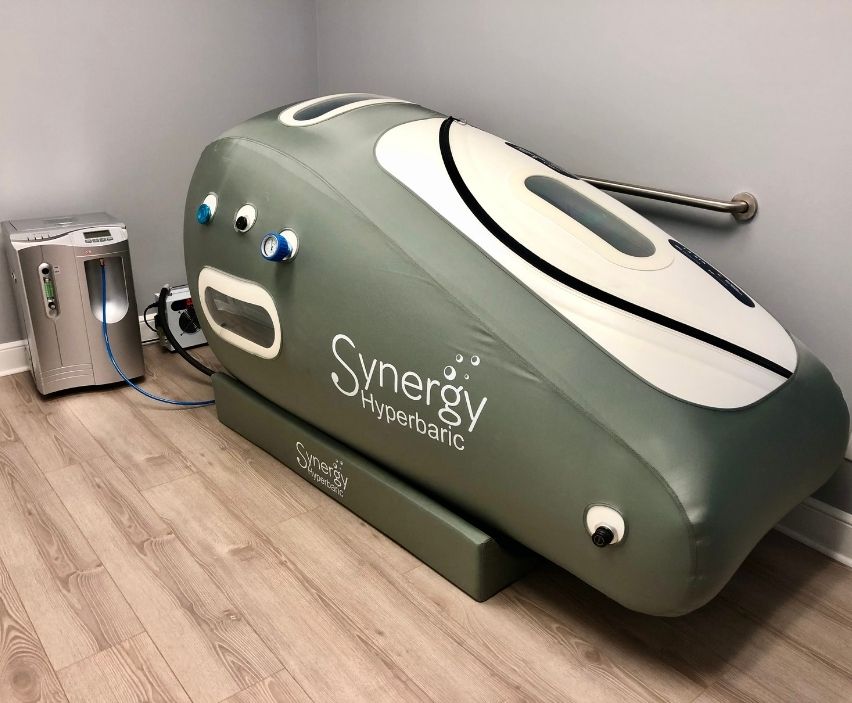 Synergy Hyperbaric chamber on a wooden floor with a gray wall background