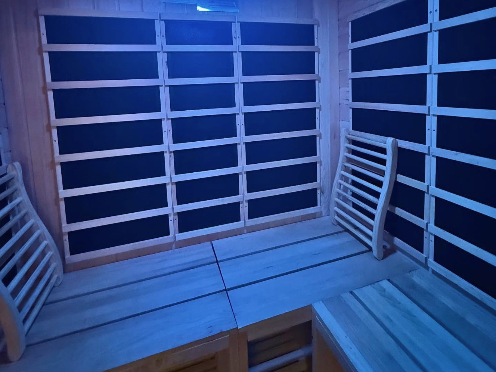 Infrared sauna with blue LED lights on the walls and wooden benches at Synergy Nutrition and Wellness in Western New York.